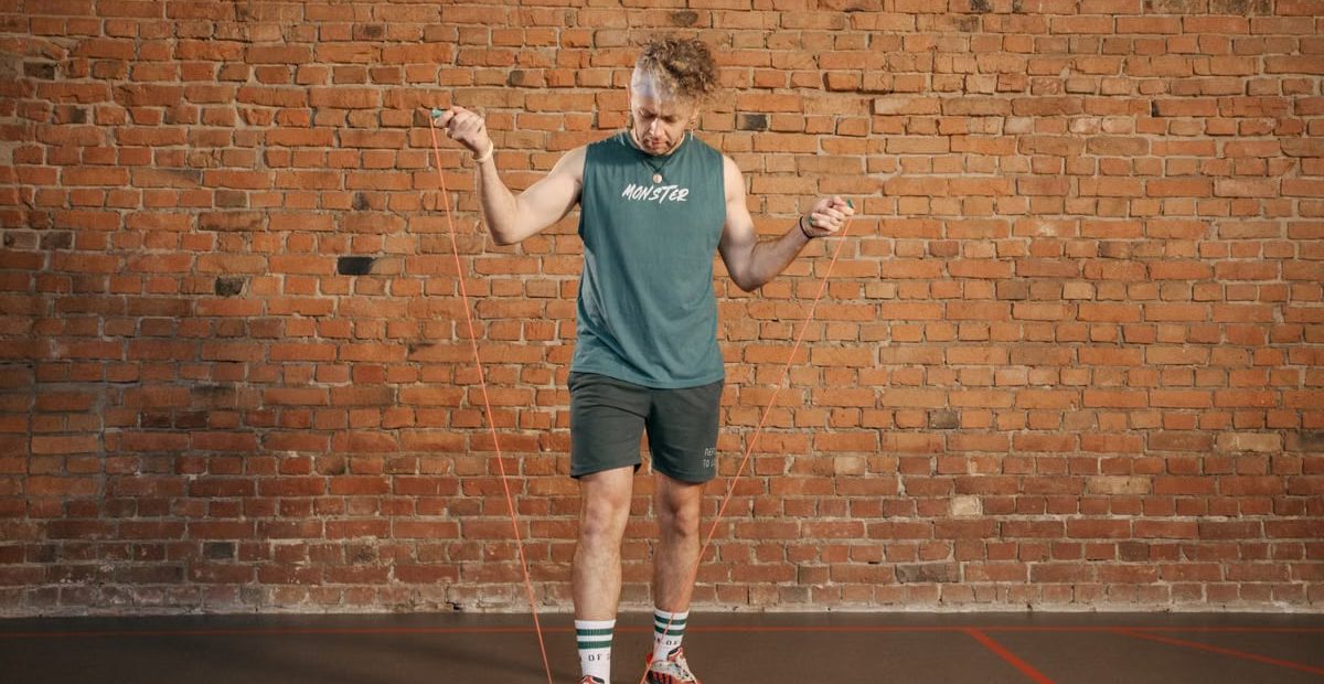 Caucasian man engaging in a jump rope workout in an indoor setting with a brick wall background.